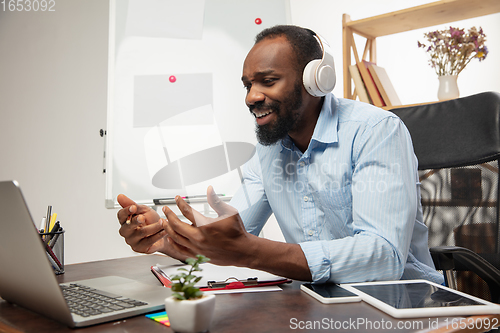 Image of Online english courses at home. Smiling man teaches students remotely in interior of living room