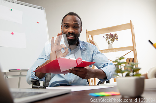 Image of Online english courses at home. Smiling man teaches students remotely in interior of living room