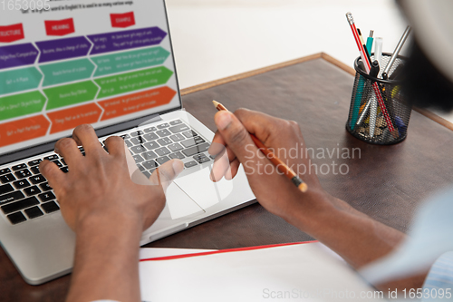 Image of Online english courses at home. Close up hands of man during teaching students remotely in interior of living room