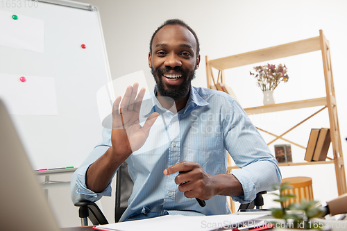 Image of Online english courses at home. Smiling man teaches students remotely in interior of living room