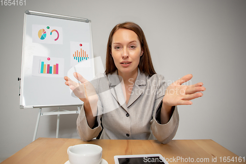 Image of Young woman talking, working during videoconference with colleagues at home office