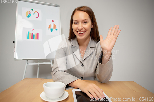 Image of Young woman talking, working during videoconference with colleagues at home office