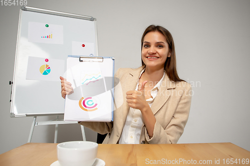 Image of Young woman talking, working during videoconference with colleagues at home office