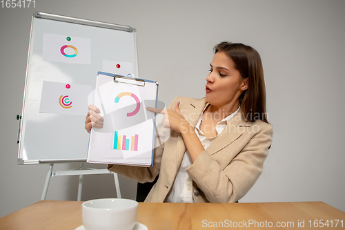 Image of Young woman talking, working during videoconference with colleagues at home office