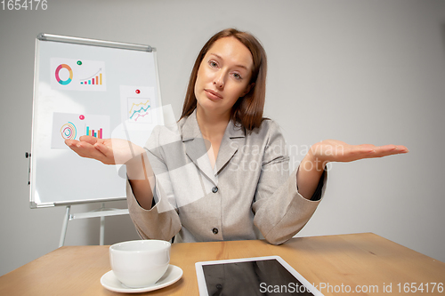 Image of Young woman talking, working during videoconference with colleagues at home office