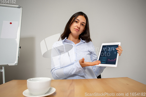 Image of Young woman talking, working during videoconference with colleagues at home office