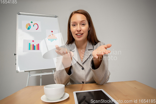 Image of Young woman talking, working during videoconference with colleagues at home office