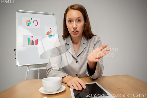 Image of Young woman talking, working during videoconference with colleagues at home office