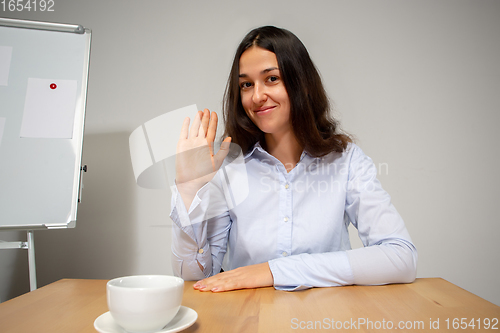 Image of Young woman talking, working during videoconference with colleagues at home office