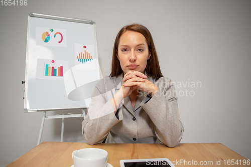 Image of Young woman talking, working during videoconference with colleagues at home office