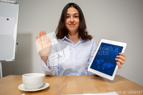 Image of Young woman talking, working during videoconference with colleagues at home office