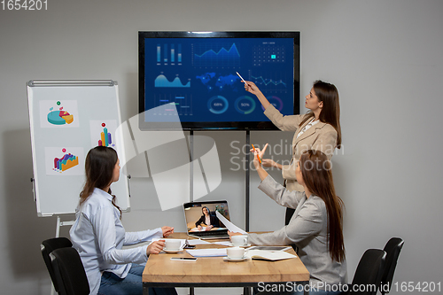 Image of Young women talking, working during videoconference with colleagues at office or living room