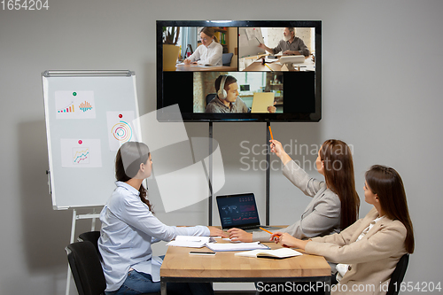 Image of Young women talking, working during videoconference with colleagues at office or living room