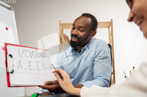 Image of English courses at home. Smiling man teaches student in interior of living room