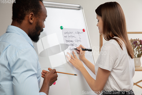 Image of English courses at home. Smiling man teaches student in interior of living room