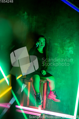 Image of Caucasian female inclusive model posing on studio background in neon light