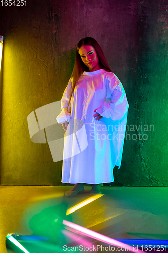 Image of Caucasian female inclusive model posing on studio background in neon light