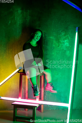 Image of Caucasian female inclusive model posing on studio background in neon light