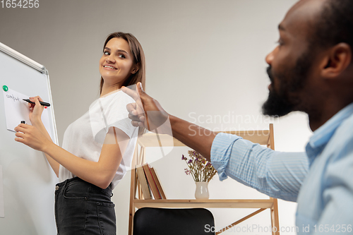 Image of English courses at home. Smiling man teaches student in interior of living room