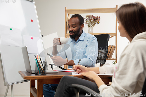 Image of English courses at home. Smiling man teaches student in interior of living room