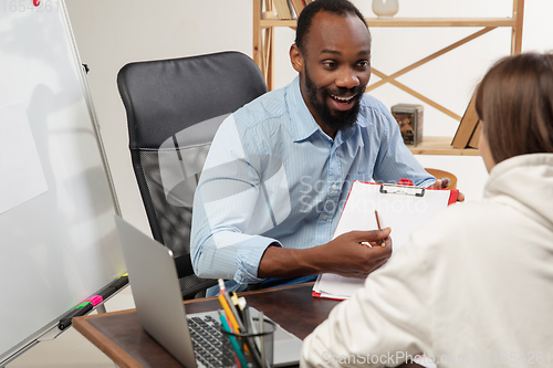 Image of English courses at home. Smiling man teaches student in interior of living room