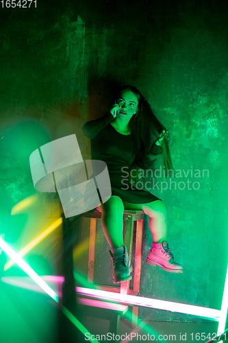 Image of Caucasian female inclusive model posing on studio background in neon light