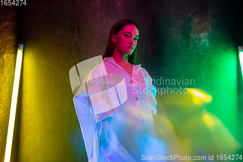 Image of Caucasian female inclusive model posing on studio background in neon light