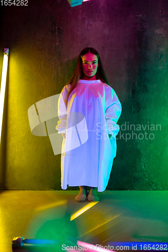 Image of Caucasian female inclusive model posing on studio background in neon light