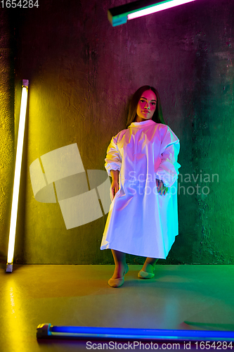 Image of Caucasian female inclusive model posing on studio background in neon light