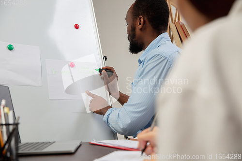 Image of English courses at home. Smiling man teaches student in interior of living room