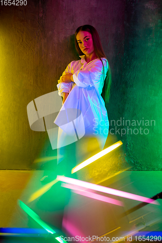 Image of Caucasian female inclusive model posing on studio background in neon light