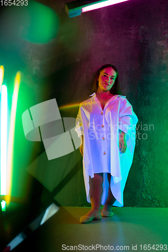 Image of Caucasian female inclusive model posing on studio background in neon light