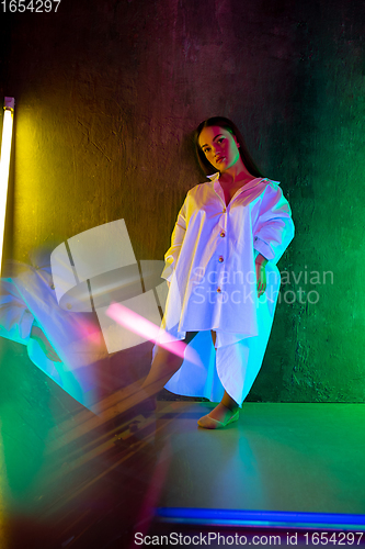 Image of Caucasian female inclusive model posing on studio background in neon light