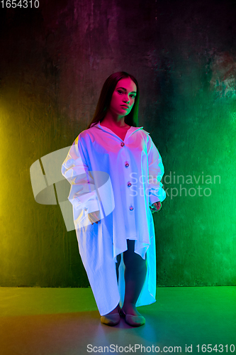 Image of Caucasian female inclusive model posing on studio background in neon light