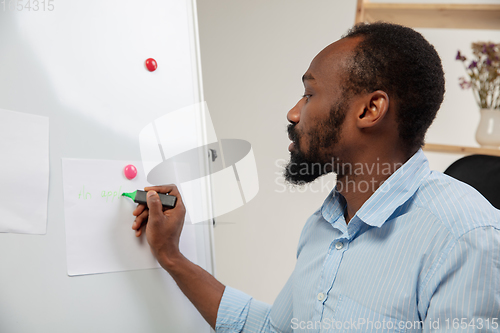 Image of English courses at home. Smiling man teaches student in interior of living room