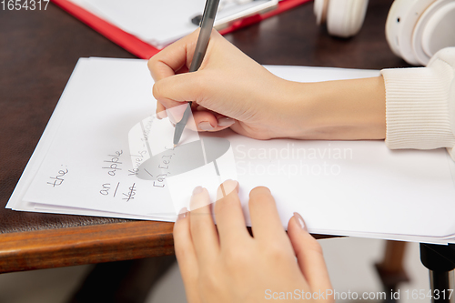 Image of English courses at home. Close up hands of teacher and student during lesson in interior of living room.