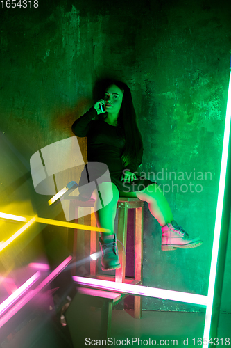 Image of Caucasian female inclusive model posing on studio background in neon light