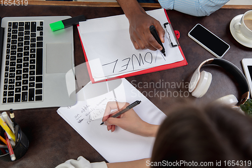 Image of English courses at home. Close up hands of teacher and student during lesson in interior of living room.