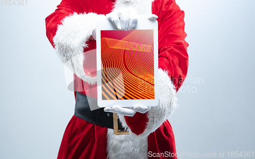 Image of Close up hands of Santa Claus holding device with neoned decoration on the screen