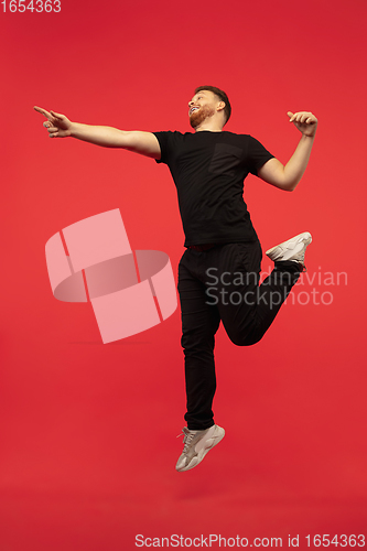 Image of Full length portrait of young successfull high jumping man gesturing isolated on red studio background