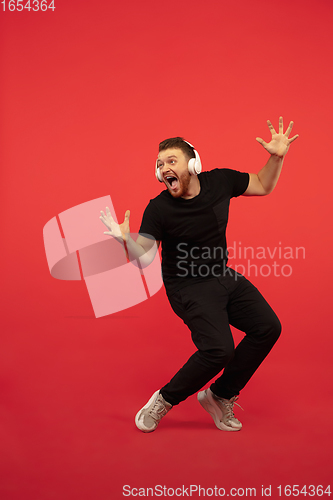 Image of Full length portrait of young successfull high jumping man gesturing isolated on red studio background