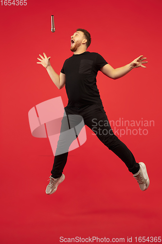 Image of Full length portrait of young successfull high jumping man gesturing isolated on red studio background