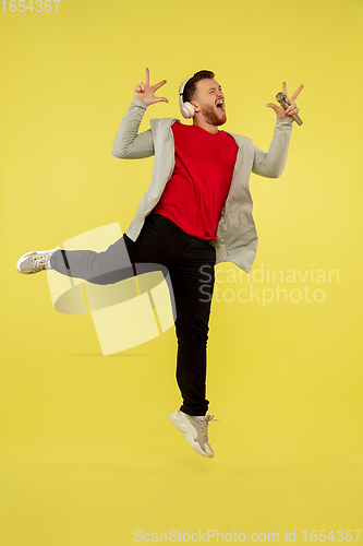 Image of Full length portrait of young successfull high jumping man gesturing isolated on yellow studio background