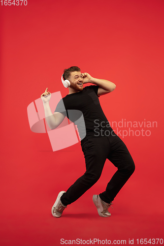 Image of Full length portrait of young successfull high jumping man gesturing isolated on red studio background