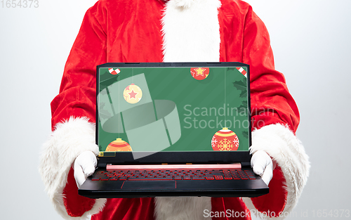 Image of Close up hands of Santa Claus holding device with stylish decoration on the screen, copyspace