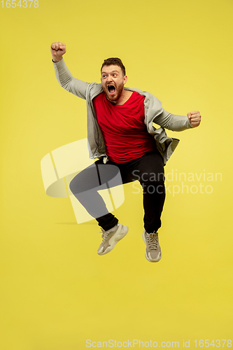 Image of Full length portrait of young successfull high jumping man gesturing isolated on yellow studio background