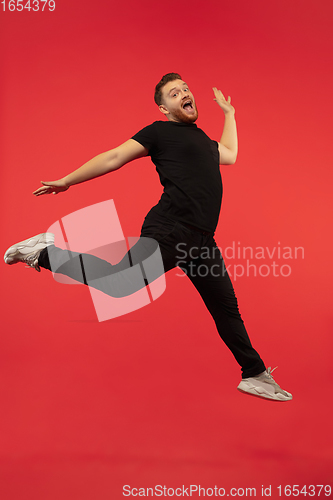 Image of Full length portrait of young successfull high jumping man gesturing isolated on red studio background