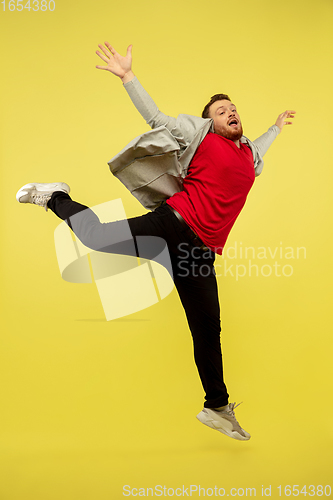 Image of Full length portrait of young successfull high jumping man gesturing isolated on yellow studio background