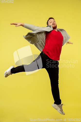 Image of Full length portrait of young successfull high jumping man gesturing isolated on yellow studio background