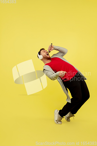 Image of Full length portrait of young successfull high jumping man gesturing isolated on yellow studio background